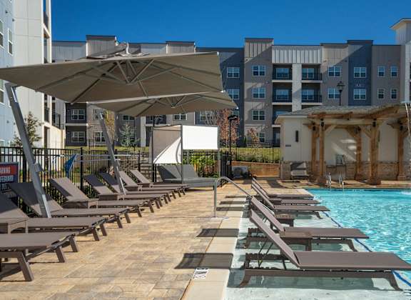 A pool area with sun loungers and a waterfall.