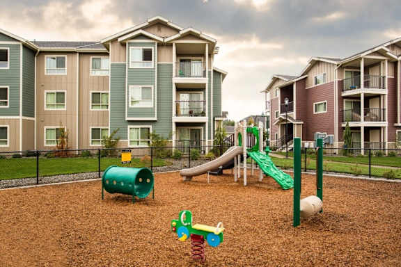 A playground with a green slide and a red ball.