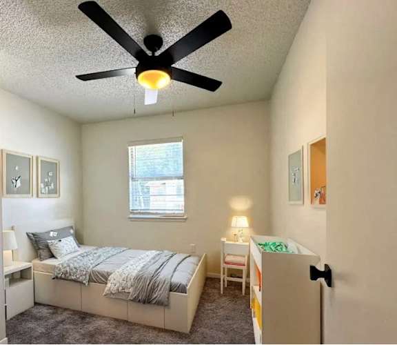 A bedroom with a bed, a chair, and a window.