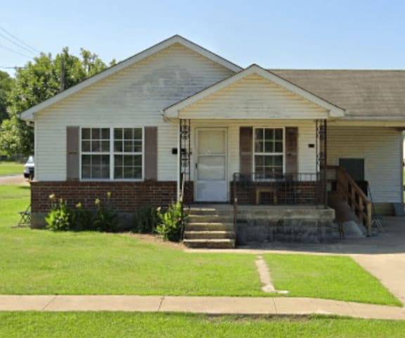 A small house with a porch and a white door.