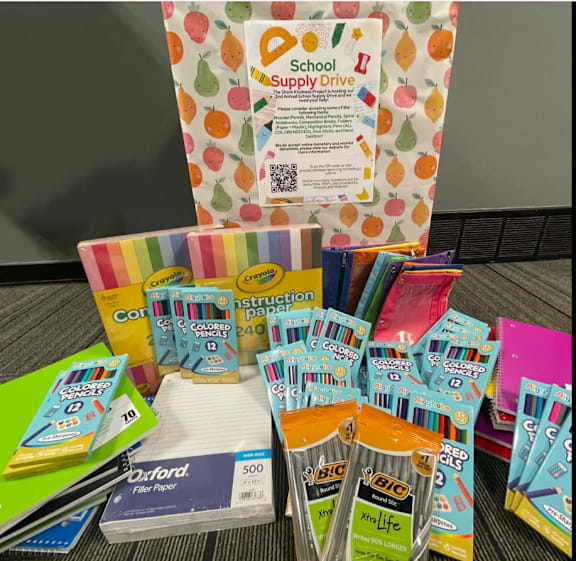 A variety of school supplies are displayed, including colored pencils, construction paper, and Oxford paper.