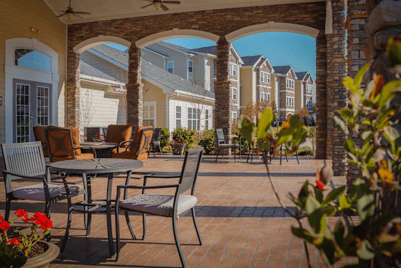 A patio with a table and chairs is surrounded by a brick wall at Stone Gate Apartments, Spring Lake, NC