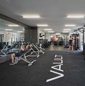 A gym with a variety of equipment including a weight bench and a rowing machine.