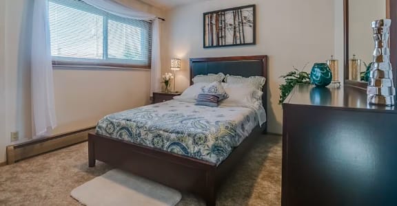 A bedroom with a bed, nightstand, and a mirror.