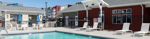 A swimming pool with sun loungers and a building in the background.