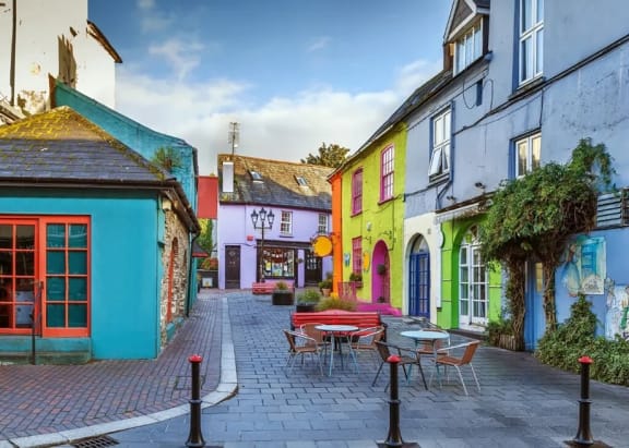 a street with colorful buildings and tables and chairs