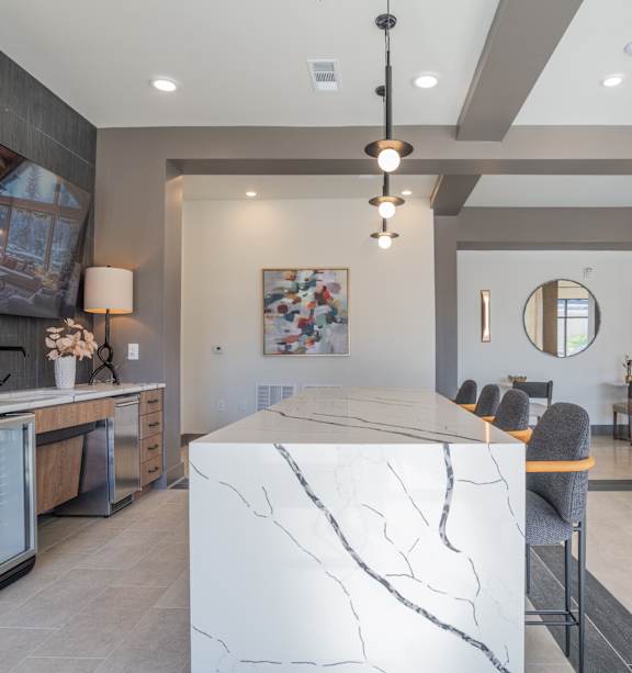 A modern kitchen with a marble island and pendant lights.
