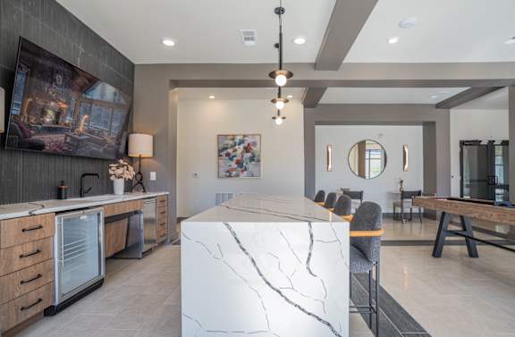 A modern kitchen with a marble island and pendant lights.