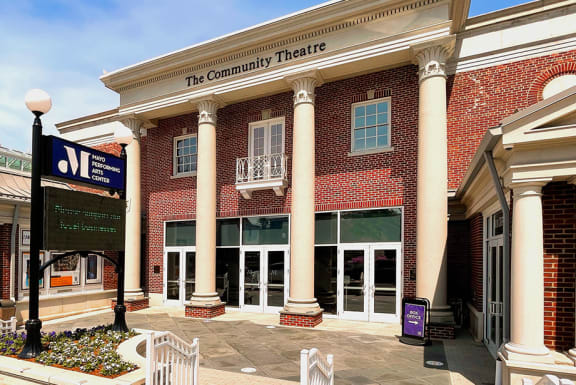 a brick building with pillars and a sign that reads the community theatre