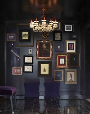 a gallery wall with portraits and a chandelier in a room with purple chairs at York House, Saint Louis, Missouri