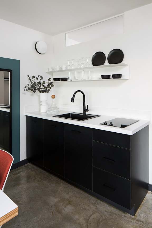 a black and white kitchen with a black sink and black cabinets at The Flat in Los Angeles, CA