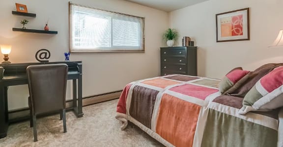 A bedroom with a bed, desk, and chair.