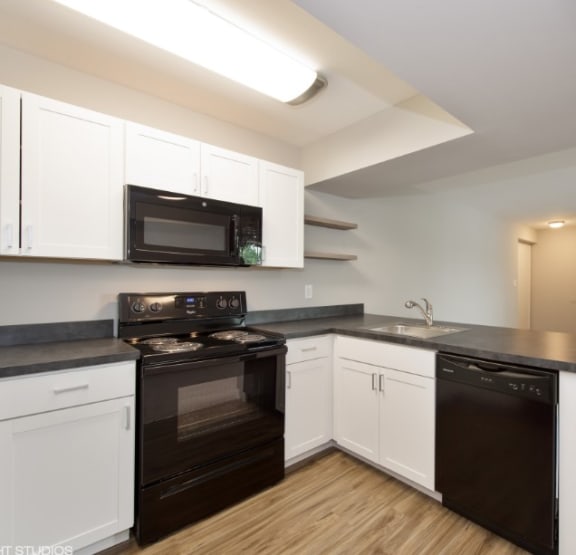 a kitchen with white cabinets and black countertops