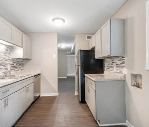 an empty kitchen with white cabinets and a black refrigerator