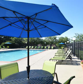 a swimming pool with tables and chairs with umbrellas at Chinoe Creek Apartments in Lexington KY