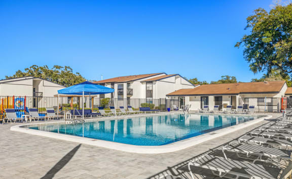 a resort style swimming pool with lounge chairs and umbrellas