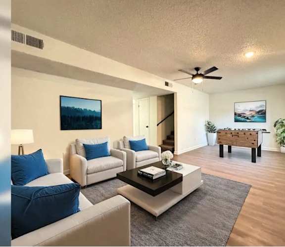 A living room with a blue couch and a painting on the wall.