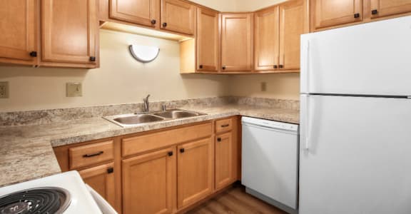 A kitchen with wooden cabinets and a white refrigerator.