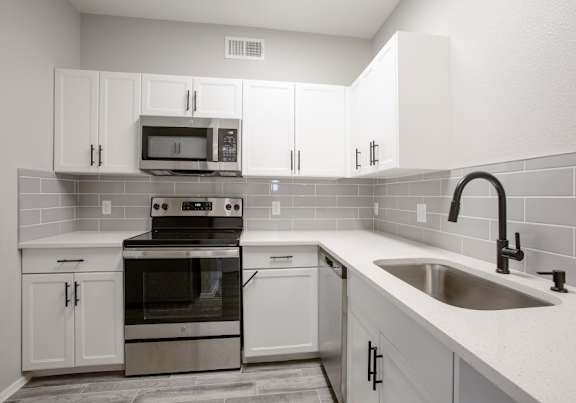 A kitchen with white cabinets and a black stove top oven.