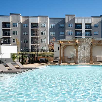 A large swimming pool in front of a multi-story apartment building.at The Delaney at East Park Apartments, Kennesaw, 30144