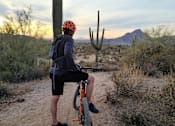 Thumbnail 28 of 46 - A person is riding a bicycle on a dirt trail at Bautista Apartments, Arizona