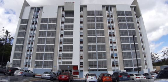 an image of an apartment building with cars parked in front