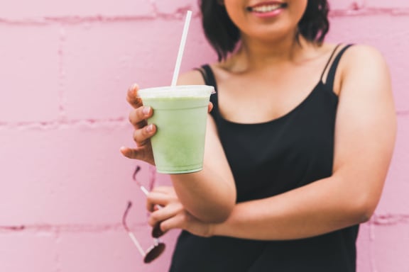 Woman holding green smoothie against pink wall at Mirabella Apartments, Bermuda Dunes, California