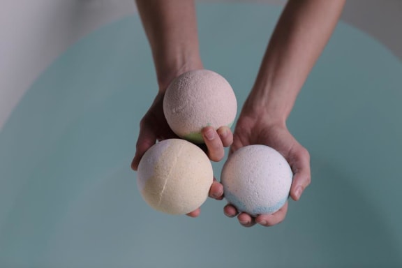Bath bombs in hand over bath tub at Mirabella Apartments, CA, 92203