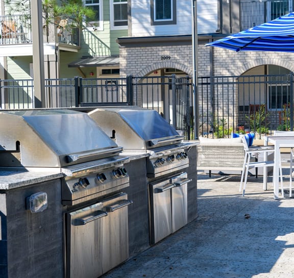 a patio with barbecue grill and tables with chairs and umbrellas  at Oakbrook Townhomes, Tennessee, 37067
