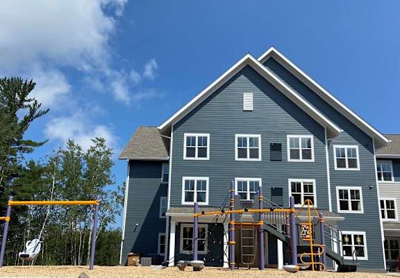 A blue house with a playground in front.