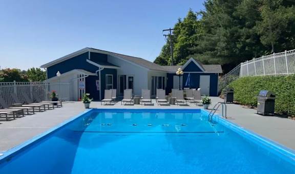 A blue swimming pool in front of a house.