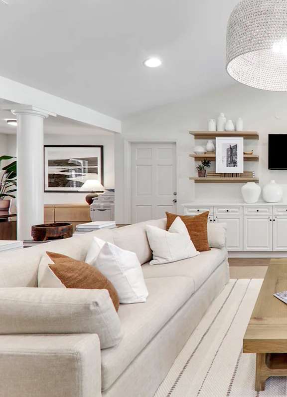 A living room with a white couch, wooden coffee table, and a large chandelier.