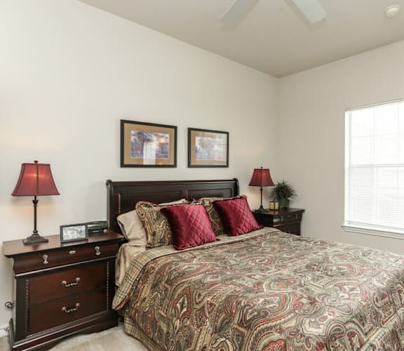 A bedroom with a large bed and two lamps on either side of the bed.