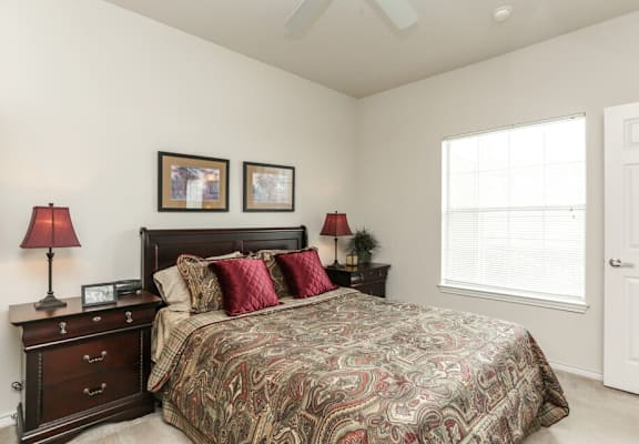 A bedroom with a large bed and two lamps on either side of the bed.