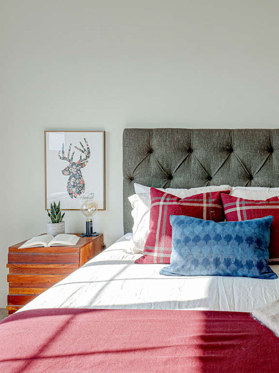 A bed with a red blanket and a blue pillow.