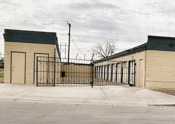 A gated entrance to a building with a grey wall and a black gate.