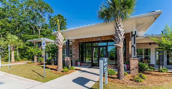 a building with palm trees and a sidewalk in front of it