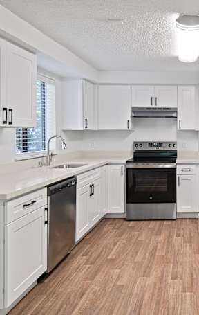 a renovated kitchen with white cabinets and stainless steel appliances