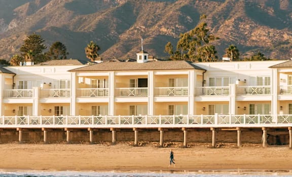 A beachfront hotel with a mountain in the background.
