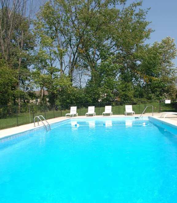 a large blue swimming pool with chairs around it