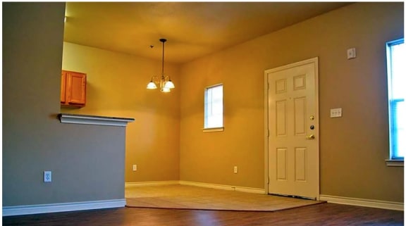 an empty room with a door and a chandelier