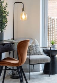 an open plan living room and kitchen with a white sofa and chairs and a glass coffee table