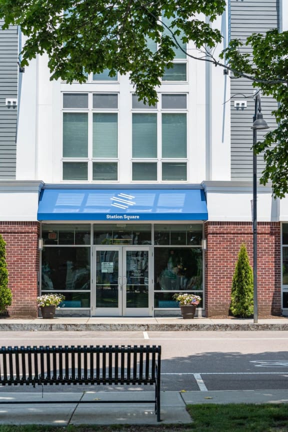 the front of a building with a blue awning and a bench