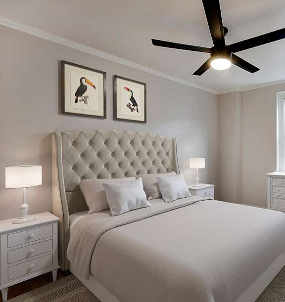 A bedroom with a large bed, a ceiling fan, and two framed pictures on the wall.