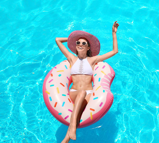 a woman laying in a pool on a pink inner tube