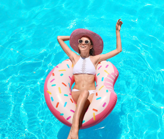 a woman laying in a pool on a pink inner tube