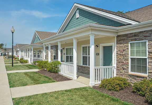 A row of houses with white porches and green roofs.