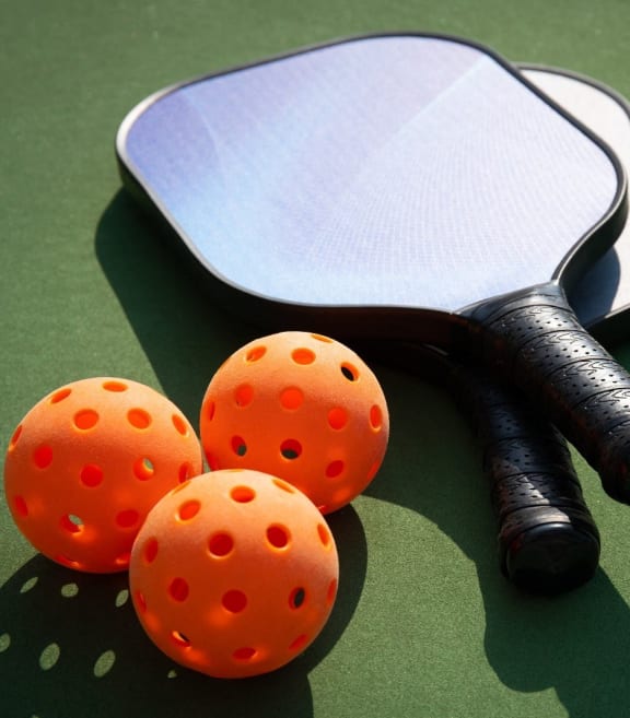 three orange balls and a tennis racket on a court