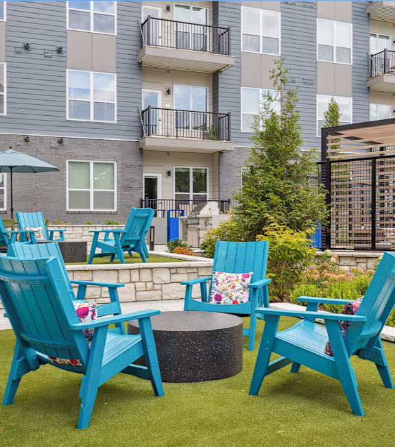 A small patio with blue chairs and a table.