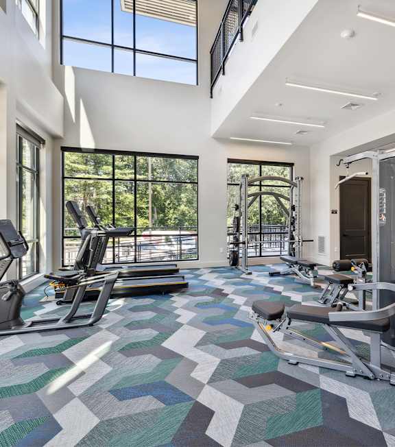 A gym with a green and grey floor and a row of treadmills.